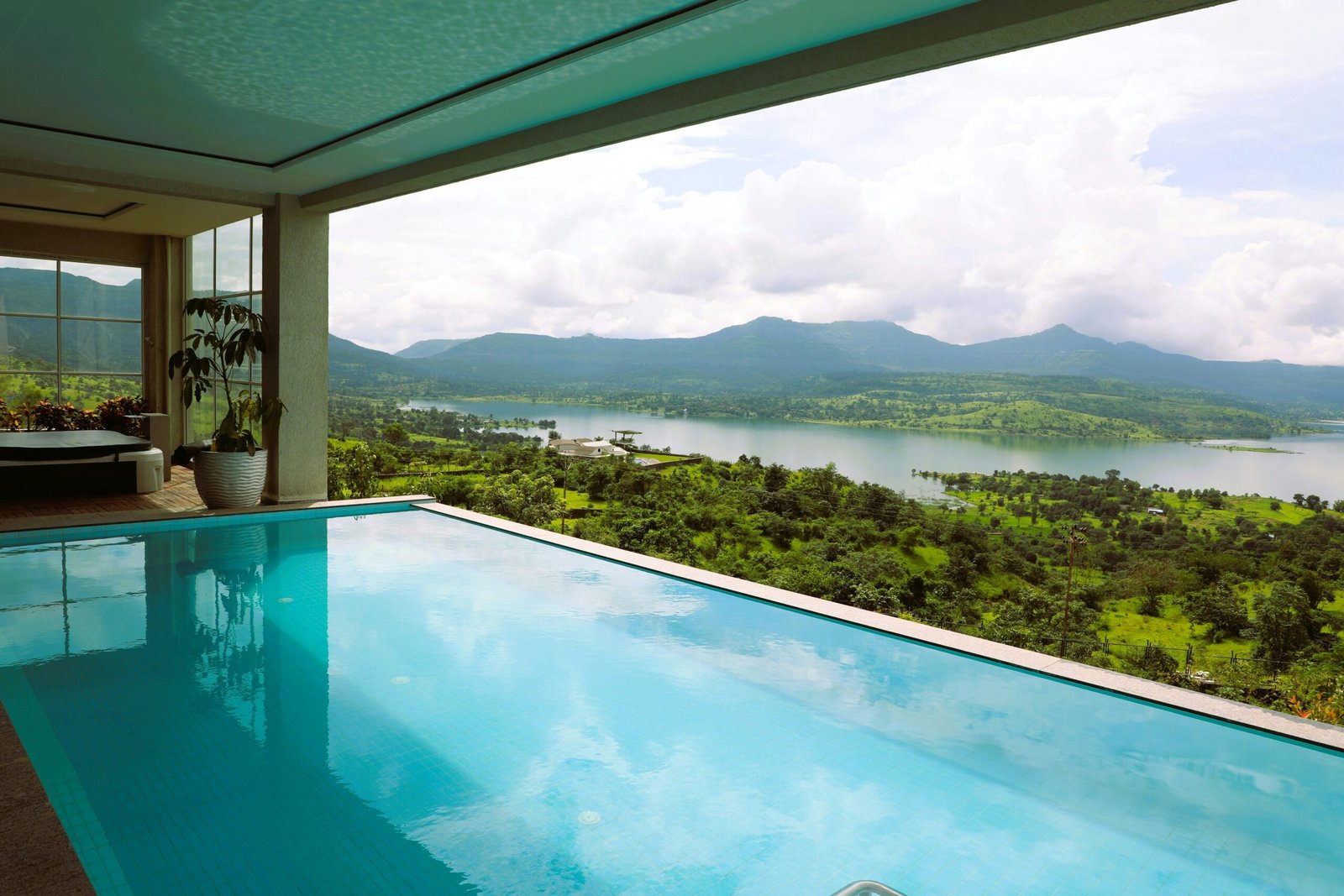 Service-2-min Experience tranquility with an indoor pool offering a breathtaking view of a serene lake and lush hills.
