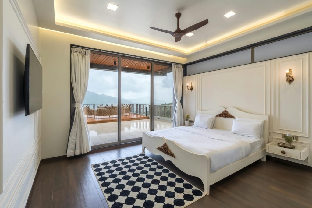 Services Spacious modern bedroom featuring a double bed, checkered rug, and scenic balcony view, perfect for luxury living.